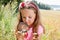 Little girl exploring the daisy through magnifying glass