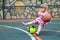 A little girl falls with a ball on the sports ground. A child with a large basketball