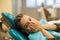 Little girl in fear closes his mouth with his hands sitting in a chair in the dental clinic