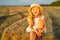 Little girl in a field with hay rolls