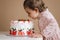 Little girl first time taste bithday cake. Cute little girl in beautiful dress tasting cake with strawberries