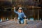 Little girl fisherman with a fishing rod and a bucket of fish on a wooden pier