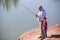 Little girl fishing together with Grandpa