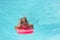 Little girl on the floating board, learns to swim in the pool