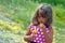 Little girl in on a flower field with a bouquet of yellow flowers