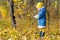 Little girl full length profile standing at yellow and orange autumn fallen leaves groundcover