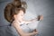 A little girl with a funny hairstyle is lying in bed with a tablet. Solid grey bed linen close-up view from above