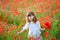 Little girl gathers a bouquet of wild red flowers
