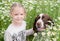 Little girl gently hugs his dog in daisy field. Friendship child girl and dog. Concept: love of animals