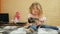 Little girl gently stroking her puppy while sitting on the bed