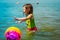 Little girl gets wet after playing a ball in the sea