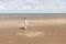 A little girl with glasses is flying her wind kite standing on a sandy beach
