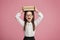 Little girl with glasses holds stack of books on her head and shouts