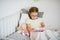 Little girl in glasses reading a book while lying in bed.