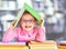 Little girl in glasses under book roof or house