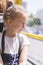 A little girl is going by bus. Schoolgirl sitting in school bus and ready for her first ride. vertical photo