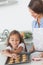 Little girl grabbing a cookie from a baking pan