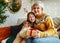 Little girl granddaughter giving Christmas gift box to smiling grandmother during winter holidays