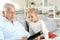 Little girl with grandfather sitting on sofa using tablet