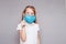 Little girl on a gray background in a medical mask and a syringe in hand