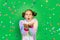 A little girl on a green isolated background in a bright suit blows away a streamer. Space for text. The concept of a holiday,