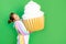 A little girl on a green isolated background in a bright suit holds a huge cake. Space for text. Concept of junk food and weight