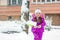 Little girl with green showel cleaning roads at winter morning.