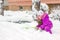 Little girl with green showel cleaning roads at winter morning.