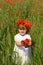 Little girl on the green wheat field with poppies