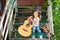 Little girl with a guitar, sits on the stairs near her house