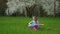 Little girl guitarist playing solo. sitting in a wonderful place tune your guitar on background of a blossoming tree green grass i