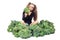 Little girl gymnast sitting among broccoli. the child looks in disgust at broccoli. isolated on white background.