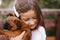 little girl with a hairpin in her hair hugs a brown dog