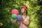 Little girl has fresh blossoming flower of roses in hat. flower composition. Beautiful girl in straw hat hold balloons