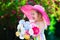 Little girl in a hat in blooming summer garden