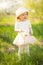 Little girl in a hat and with a blossoming branch merry, in a blossoming garden or park. Warmly, love, spring and summer mood