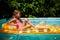 Little girl in hat relaxing in swimming pool, swims on inflatable yellow mattress