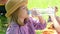 a little girl in a hat and shirt drinks water from a plastic bottle.