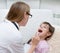 Little girl having his throat examined by health professional