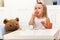 Little girl having a tea party with her toy bear