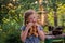 A little girl heaps a bagel against the background of a traditional Russian samovar. A child nibbles a gravy in front of a village