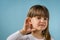 Little girl with hearing problem on light blue background. Close up, copy space
