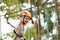 Little girl in helmet climbs ropes in adventure park outdoors. Extreme sport, active leisure on nature