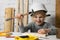 Little girl with helmet try to hammer a nail in workshop. craft education