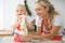 Little girl and her blonde mom in red aprons playing and laughing while kneading the dough in the kitchen. Homemad