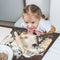 Little girl with her dirty nose helps her mother make dumplings