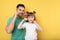 Little girl and her father flossing teeth on color background