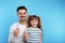 Little girl and her father with toothbrushes on color background, space for text