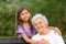 Little girl and her grandmother hugging on bench