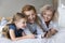 Little girl her mom and granny using smartphone on bed